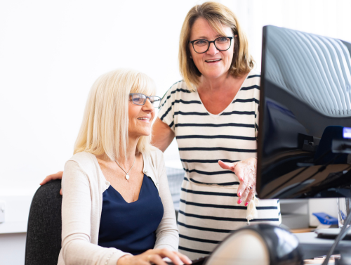 Two women chat in front of a computer