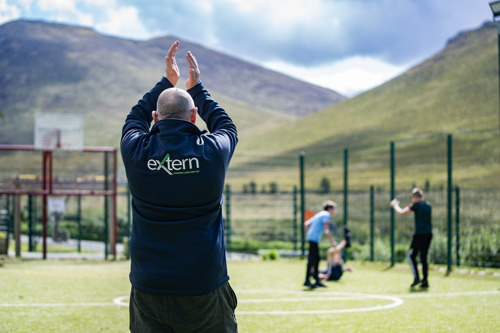 Extern staff engaging in a football match with young people