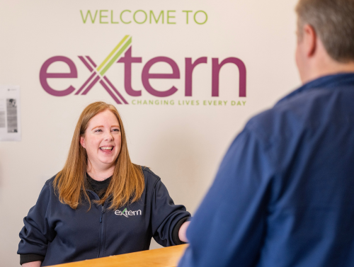 Extern staff member welcoming service user at a desk